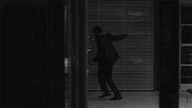a black and white photo of a man in a suit dancing in a living room