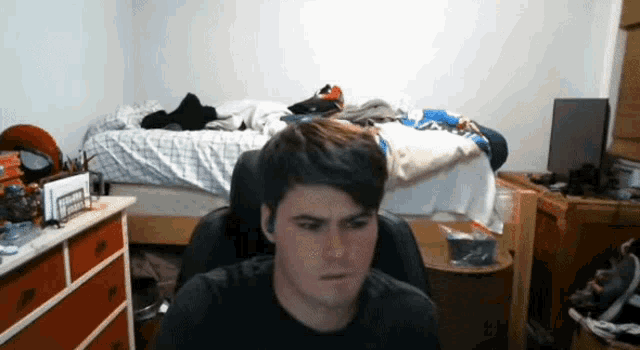 a man sitting in a chair in front of a bed