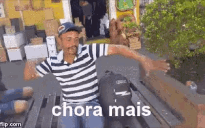 a man in a striped shirt is sitting on a boat with the words `` chora mais '' written on the screen .
