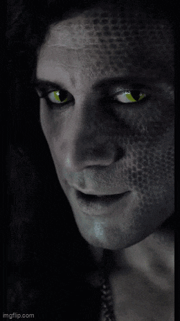 a close up of a man 's face with a snake skin pattern and green eyes