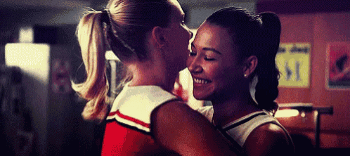 two cheerleaders are hugging and kissing each other in a room .