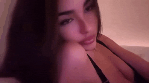a woman in a black bra is sitting on a bed .