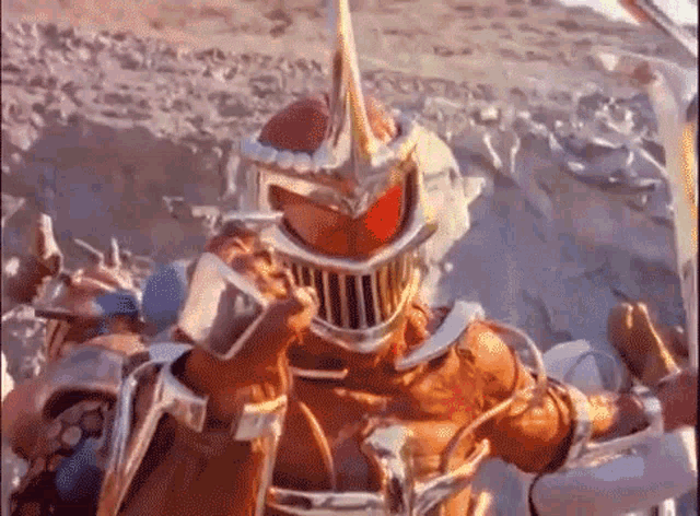 a man in a knight 's armor is holding a sword and a helmet .
