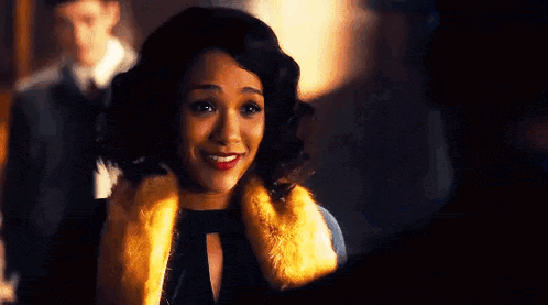 a woman is wearing a fur coat and smiling while standing next to a man .