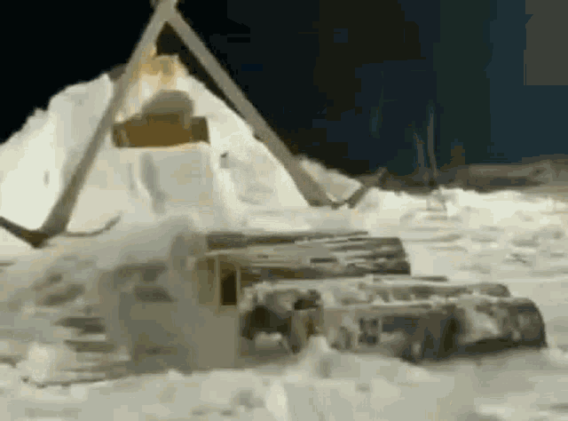 a person is standing in the snow next to a pile of logs .