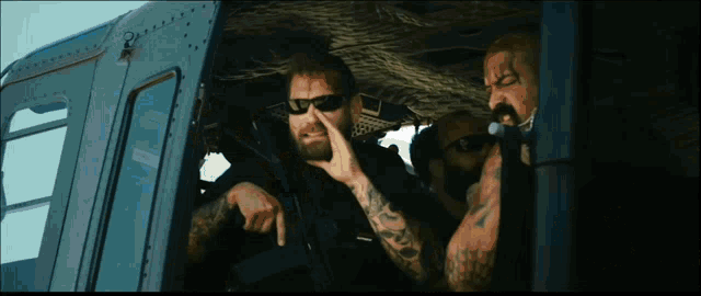 a man with a tattoo on his arm is wearing sunglasses and holding a gun