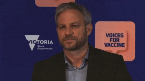 a man stands in front of a victoria state government sign
