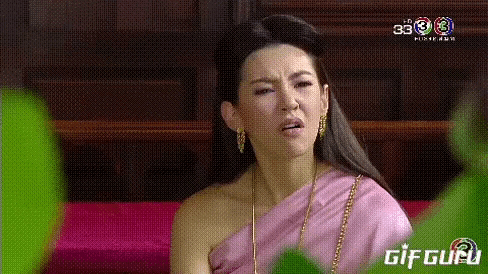 a woman in a pink dress is making a funny face while sitting on a couch .