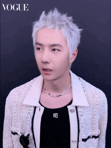 a man with white hair is wearing a white sweater and a black shirt with chinese writing on it