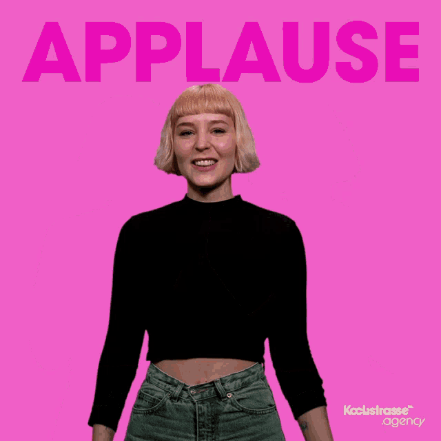 two women applaud in front of a pink background with the word applause