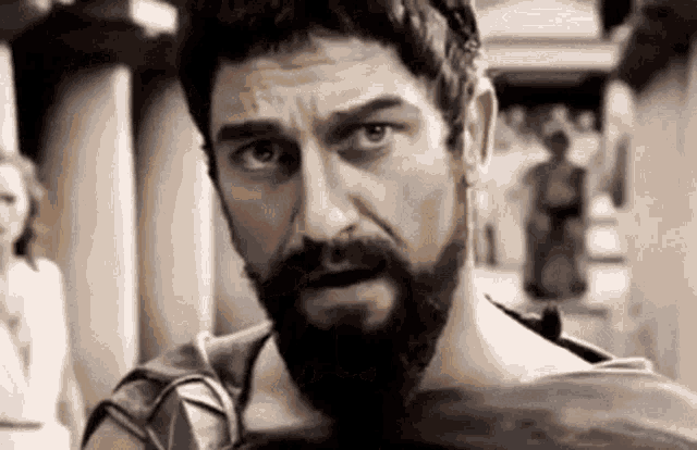a man with a beard is standing in front of a group of people .