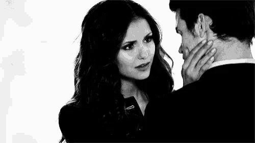 a man and a woman are looking into each other 's eyes . the woman is touching the man 's neck .