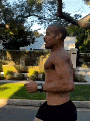 a shirtless man is running down a street wearing a smart watch