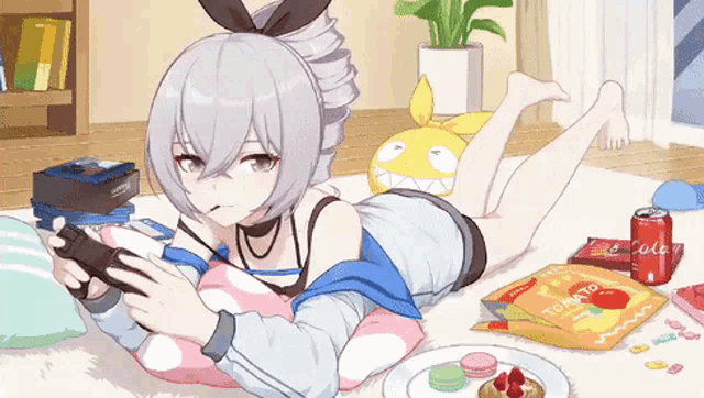 a girl laying on the floor playing a video game with a bag of tomato gummy bears in front of her