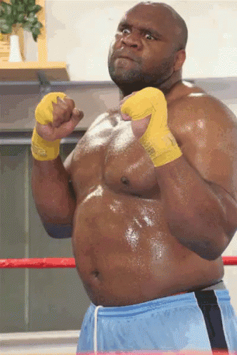 a man wearing blue shorts and yellow boxing gloves is standing in a boxing ring