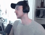 a man wearing headphones and a baseball cap is sitting in front of a microphone in a room .