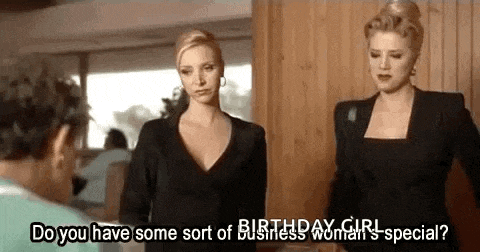 two women are standing next to each other and talking to a man in a room .