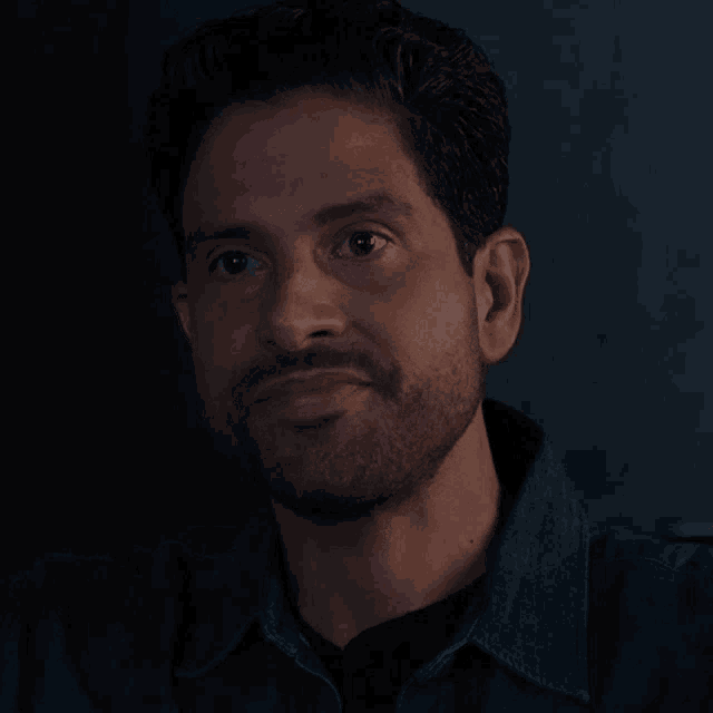 a man with a beard is wearing a denim jacket