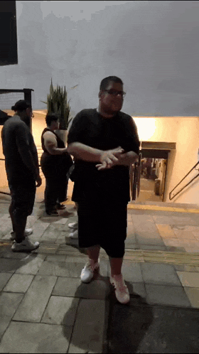 a man in a black shirt and shorts stands in front of a building