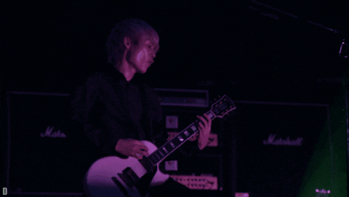 a person playing a guitar in front of a marshall amplifier
