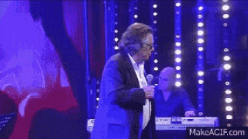 a man is singing into a microphone on stage .