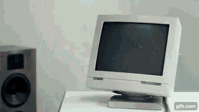 a computer monitor sits on a white table next to a speaker and a gifs.com button