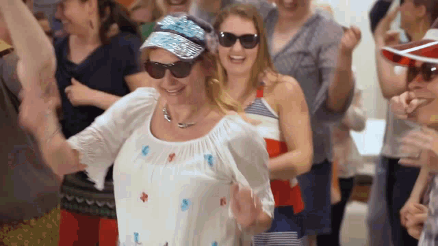 a woman wearing sunglasses and a baseball cap is dancing in a crowd of people