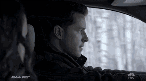a man is driving a car with a woman in the back seat and the word manifest is on the screen