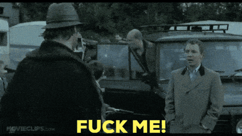 a man in a suit and hat is standing next to another man with a gun and the words " fuck me " above him