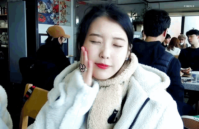 a woman with her eyes closed is wearing a white coat and a scarf