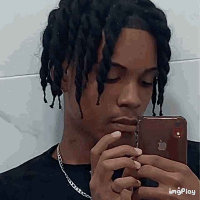 a man with dreadlocks is taking a picture of himself with an apple iphone