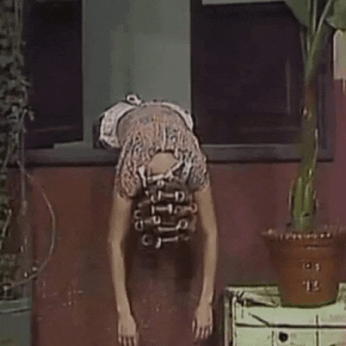 a woman is doing a handstand in front of a plant .