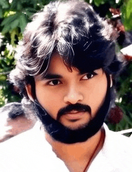 a young man with a beard and long hair is looking at the camera .