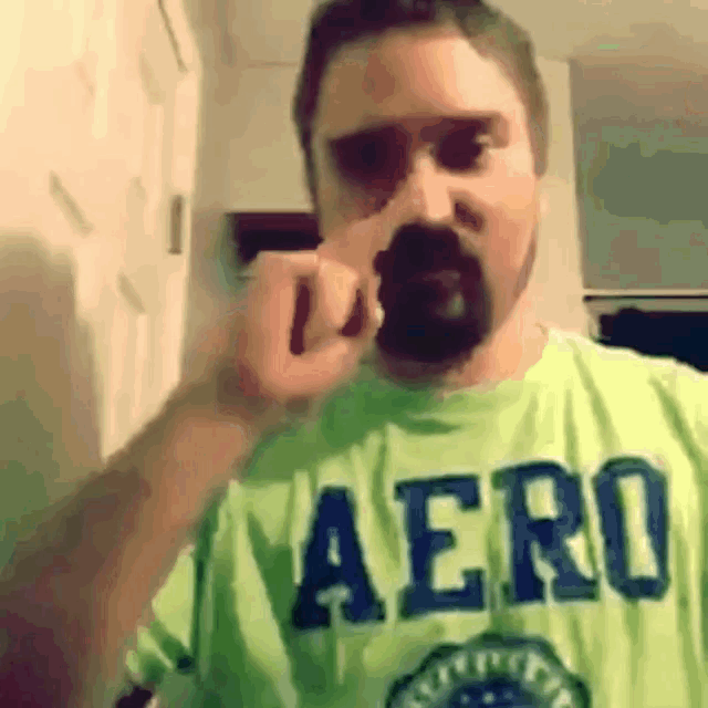 a man with a beard wearing a green aero t-shirt