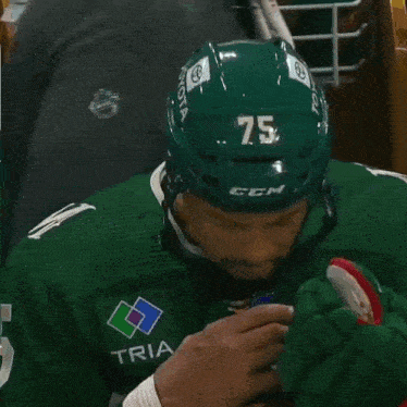 a hockey player wearing a green jersey with the number 75