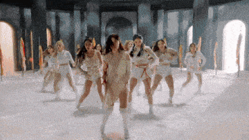 a group of young women are dancing in a room with columns .