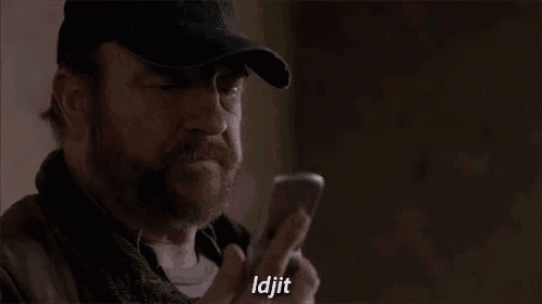 a man with a beard is talking on a cell phone while wearing a hat .