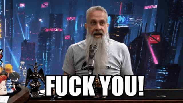 a man with a beard stands in front of a microphone with the words " fuck you " above him