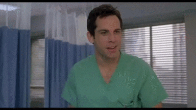 a man wearing a green scrub top is standing in a hospital room .