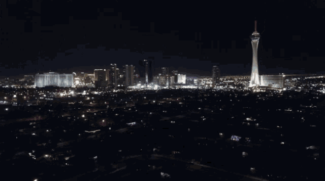 a city skyline at night with a tower in the foreground