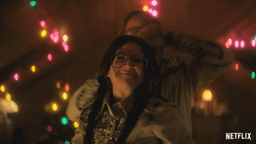 a man and a woman are waving their hands in front of a netflix ad