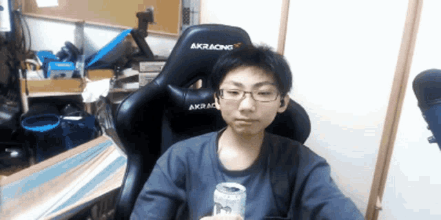 a man sitting in an akracing chair holding a can of beer