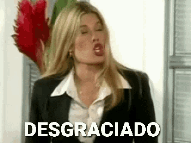 a woman in a black suit and white shirt is making a funny face and says desgraciado .