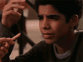 a young man is crying while a person holds a piece of meat to his face .