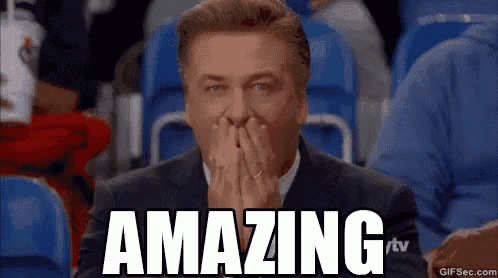 a man in a suit is sitting in a stadium with his hands on his face and the words `` amazing '' written on the screen .
