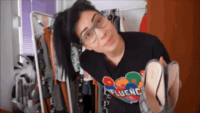 a woman wearing glasses and a black shirt that says influence on it