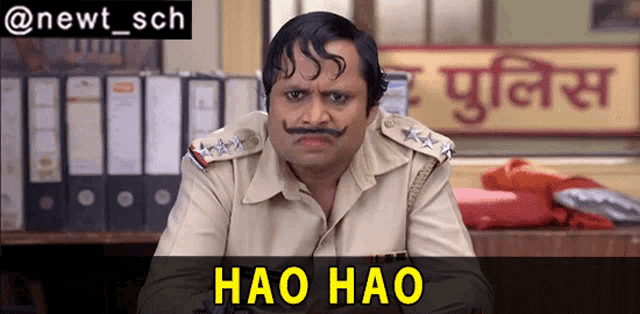 a man with a mustache is sitting in front of a sign that says haio haio