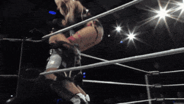 two women are wrestling in a ring and one of them is wearing a pink and black outfit