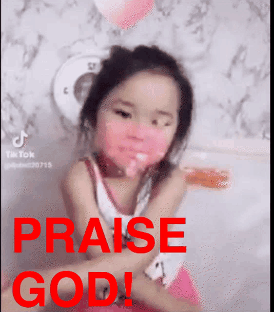 a little girl with pink paint on her face and the words praise god in red