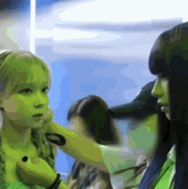 a woman in a green shirt is talking to a little girl